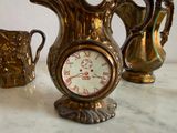 a gold vase and a clock on a marble table