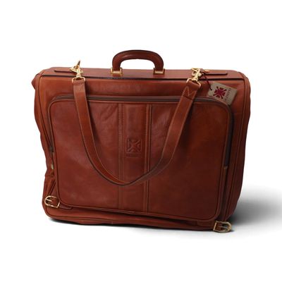 une mallette en cuir marron sur fond blanc, avec une étiquette sur la poignée