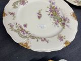 four plates with purple flowers on them sitting on a table