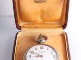 a small pocket watch in a case on a table