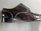 brown leather shoes hanging on a wall on a gray surface