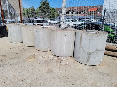 four cement cylinders sitting on the ground next to a fence