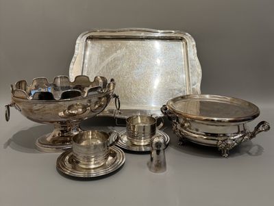 des assiettes et des plateaux en métal argenté posés sur une table avec des couverts en argent