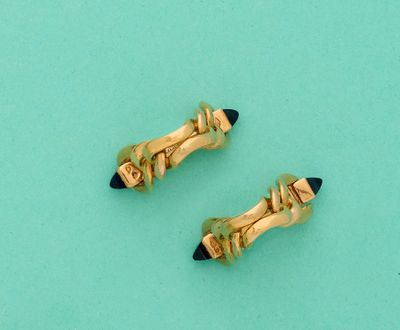 une paire de boucles d'oreilles en forme de crayons dorés et noirs sur fond turquoise