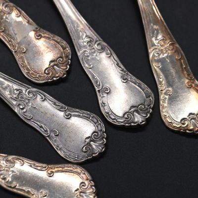 five silver spoons and a fork on a black surface