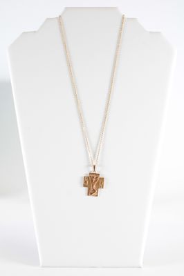 un gros plan d'un collier orné d'une croix, porté par un mannequin