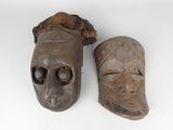 two wooden masks are sitting next to each other on a white surface