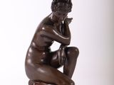 bronze statue of a man sitting on a stool with his hand on his chin