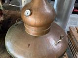 a large copper pot sitting on top of a wooden table