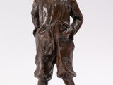 bronze statue of a boy with a hat on a rock