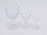 three glass goblets and a wine glass on a white surface