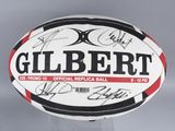 an image of a signed gilbert rugby ball on a clear base