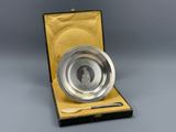 an antique silver plate with a spoon and spoon rest in a box