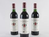 three bottles of red wine sitting next to each other on a white surface