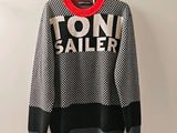 a black and white sweater with a red collar on a hanger