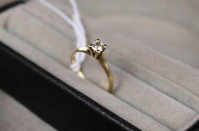 une bague en or sertie d'un diamant, posée dans une boîte