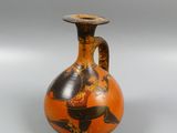 an orange vase with a black and gold design on it