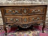 une commode en bois posée sur un tapis devant un mur en pierre