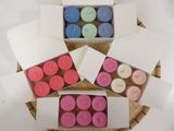 several different colored candles are in boxes on a table
