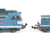 two toy trains sitting side by side on a white surface