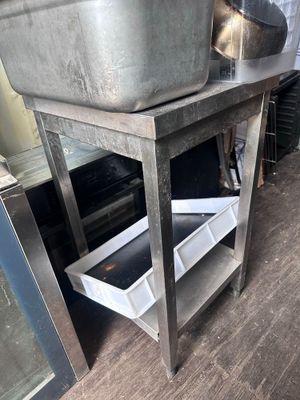 a metal sink sitting on top of a wooden table