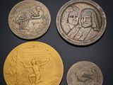 three silver and gold coins with a picture of a man holding a sword