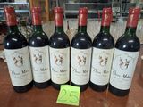six bouteilles de vin rouge sont alignées sur une table