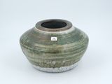 a green vase with a tag on it on a white surface