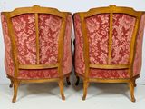 pair of red upholstered chairs with wooden legs and arms
