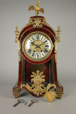 a red and gold clock with a bird on it