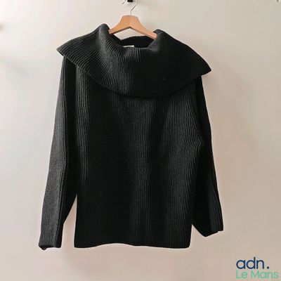 Le pull est suspendu à un cintre accroché au mur.