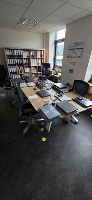 a long table with laptops on it in a large room