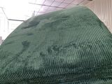 une chaise verte qui se trouve dans une pièce où il y a beaucoup de désordre