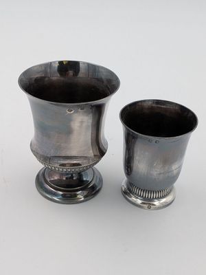 deux tasses en argent posées l'une à côté de l'autre sur une table