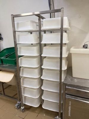 de nombreux récipients en plastique empilés sur une étagère métallique dans une cuisine