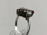 silver ring with garnetts and diamonds on a clear surface