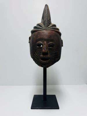 a close up of a wooden mask on a stand on a white surface