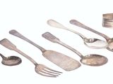several spoons, forks, and a tin are arranged on a white surface