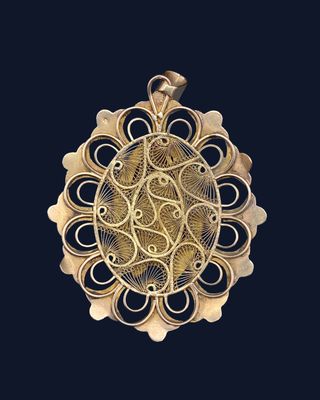 a close up of a gold pendant on a black background
