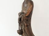 an antique bronze statue of a woman holding a pot on a wooden table