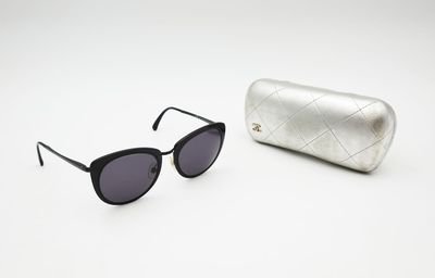 black sunglasses and a silver case on a white surface