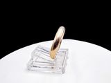 a gold ring sitting on top of a clear glass holder