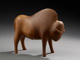 une petite sculpture en bois représentant un taureau sur une surface grise