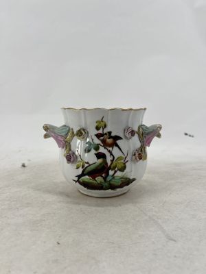 a small white vase with a bird and flowers on it