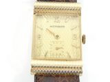 une photo d'une montre en or avec un bracelet en cuir d'alligator marron