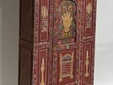 a small red cabinet with gold decorations on it