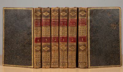 trois vieux livres posés les uns à côté des autres sur une table en bois