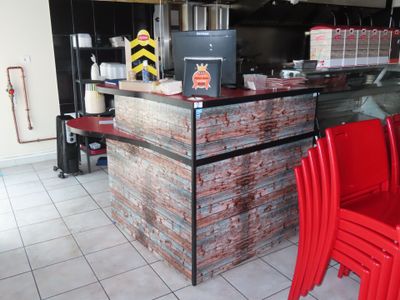 des tables et des chaises dans un restaurant doté d'un comptoir en briques et de chaises rouges