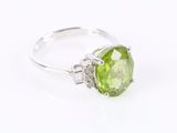 gros plan d'une bague avec une pierre verte entourée de diamants blancs