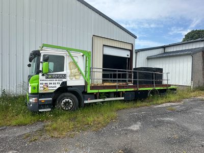 un camion vert et blanc garé devant un immeuble